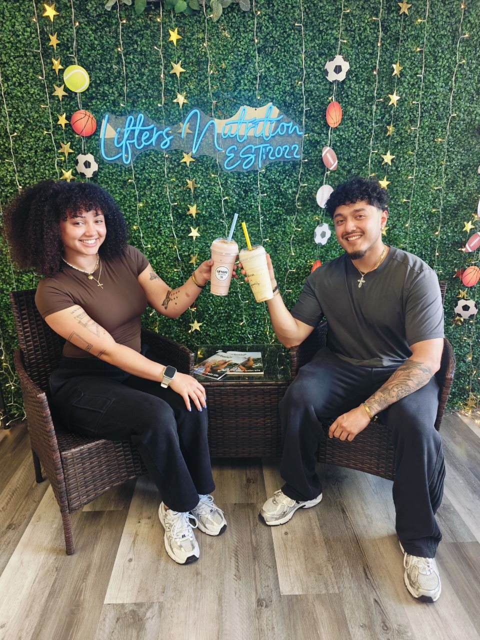 Two customers toasting with Lifters shakes under the neon sign